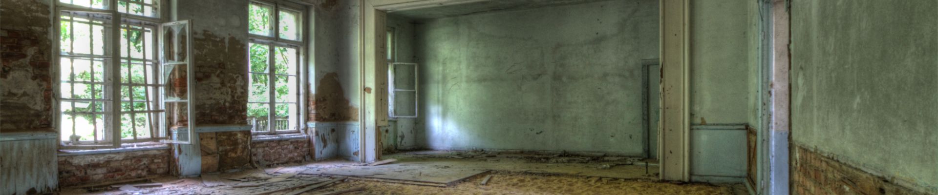 Verlassener Raum mit Sand und alten Fenstern.